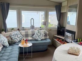 A living room with a sofa, table, and television at Ty Cariad