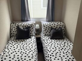 A bedroom with two beds and a lamp at Ty Cariad