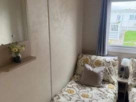 A bedroom with a bed, lamp, and mirror at Ty Cariad