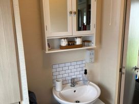 A bathroom with a sink and a mirror cabinet at Ty Cariad