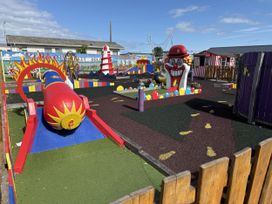 A mini golf course with clown statue and colorful decorations at Ty Cariad in Towyn