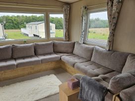 A living room with a sofa and window at Thurston Manor Caravan Park, Pony Meadow in Dunbar