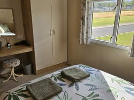A bedroom with a bed and a wardrobe at Thurston Manor Caravan Park, Pony Meadow, Dunbar