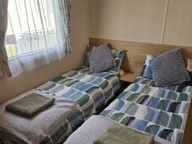A bedroom with two beds and a window at Thurston Manor Caravan Park, Pony Meadow, Dunbar