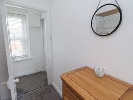 A hallway with a mirror and a wooden drawer at 23 Northumbria Terrace in Amble