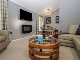 A living room with a sofa, coffee table, and television at 32 Grasmere, White Cross Bay near Windermere