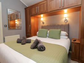 A bedroom with a double bed and wooden storage at 32 Grasmere, White Cross Bay near Windermere