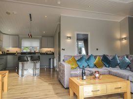 A living room with a sofa and kitchen area at 7 Lake View in Windermere