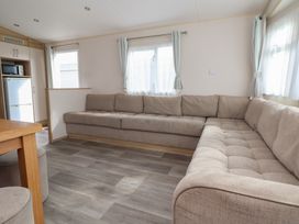 A living room with a sofa and kitchen appliances at E10 Static Caravan in Rhyl
