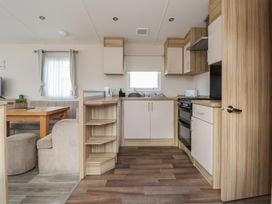 A living room with a kitchen area and dining table at E10 Static Caravan in Rhyl