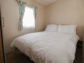 A bedroom with a bed and curtains at E10 Static Caravan Rhyl