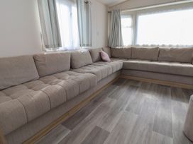 A living room with a sofa and curtains at A5 Static Caravan in Rhyl