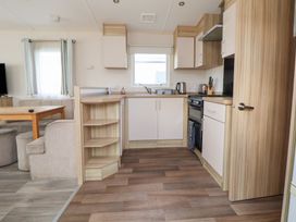 A kitchen with a sink, oven, and table at A5 Static Caravan in Rhyl