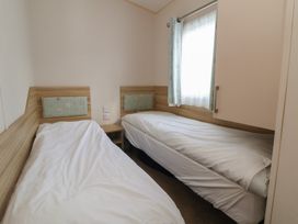 A bedroom with two single beds and a window at A5 Static Caravan Rhyl