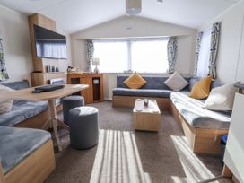 A living room with a television and seating area at Chappie's Caravan - Rhyl