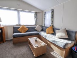A living room with a grey sofa and coffee table at Chappie's Caravan - Rhyl