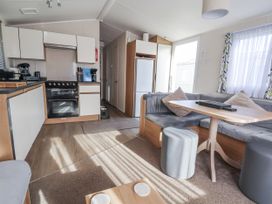 A living room with a kitchen area and dining table at Chappie's Caravan - Rhyl