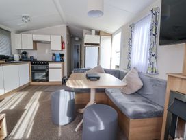 A living room and kitchen with a table and couch at Chappie's Caravan - Rhyl