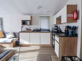 A kitchen with appliances and seating at Chappie's Caravan - Rhyl