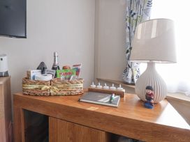 A living room with a basket and lamp at Chappie's Caravan - Rhyl