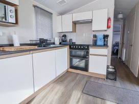 A kitchen with appliances and utensils at Chappie's Caravan - Rhyl