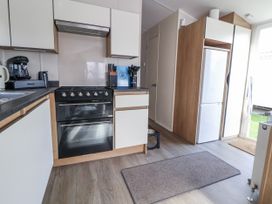 A kitchen with a stove and refrigerator at Chappie's Caravan - Rhyl