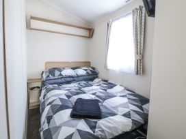 A bedroom with a bed and bedside table at Chappie's Caravan - Rhyl