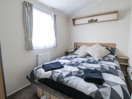 A bedroom with a bed and shelf at Chappie's Caravan - Rhyl