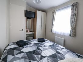 A bedroom with a bed, television, and wardrobe at Chappie's Caravan - Rhyl