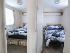 A bedroom with two beds and a window at Chappie's Caravan - Rhyl