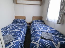 A bedroom with two beds and a shelf at Chappie's Caravan - Rhyl
