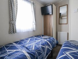A bedroom with two beds and a television at Chappie's Caravan - Rhyl