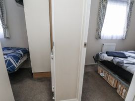 A bedroom with beds and curtains at Chappie's Caravan - Rhyl