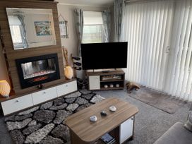 A living room with a fireplace and TV at 5 Rush Grove Caravan Leven
