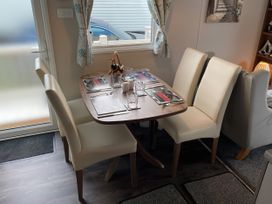 A dining table with chairs and glasses at 5 Rush Grove Caravan, Leven