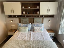 A bedroom with a bed against a wooden wall at 5 Rush Grove Caravan Leven