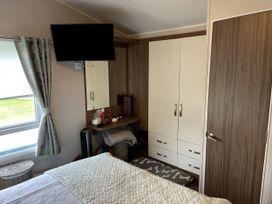 A bedroom with a bed, television, and storage at 5 Rush Grove Caravan in Leven