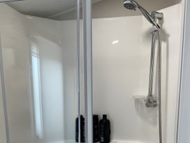 A shower with a shower head and hair products at 5 Rush Grove Caravan in Leven