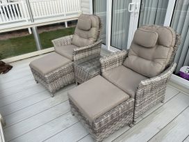 Two wicker chairs with footrests on an outdoor patio at 5 Rush Grove Caravan Leven
