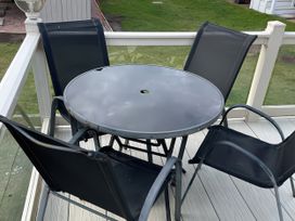 A round table with chairs on a deck at 5 Rush Grove Caravan in Leven