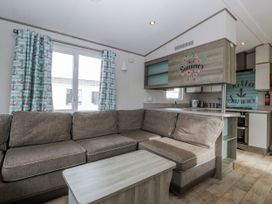 A living room with a sofa and a kitchen area at Caravan - 2 Bayside in Watchet