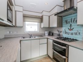 A kitchen with cabinets and appliances at Caravan - 2 Bayside in Watchet