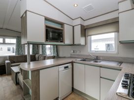 A kitchen with a sink, dishwasher, and microwave at Caravan - 2 Bayside Watchet