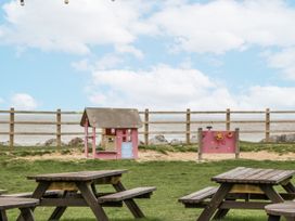 A play area with a pink playhouse and water playstation near picnic tables at Caravan - 2 Bayside Watchet