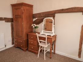 A bedroom with a wardrobe, dresser, mirror, and flowers at Duke Cottage in Woodbridge