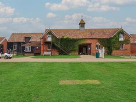 A building surrounded by grass and a pathway at Duke Cottage in Woodbridge
