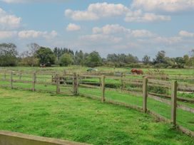 An outdoor area with a fence, grass, horse, and trees at Duchess Cottage in Woodbridge