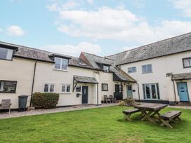 An outdoor view of a house with a garden table at Rushmoor Cottage in Colaton Raleigh