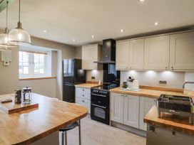 A kitchen with a refrigerator, stove, and countertop at Rushmoor Cottage in Colaton Raleigh