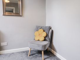 A chair with a yellow flower pillow in a living room at Rushmoor Cottage in Colaton Raleigh